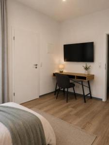 a bedroom with a desk and a television on a wall at Blue Stay Bremen in Bremen