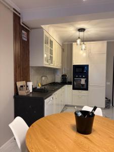 a kitchen with a wooden table and white cabinets at F&L Relax Mamaia Nord -Apartament cu parcare gratuită in Mamaia Sat/Năvodari +5 photos