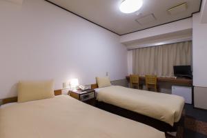a hotel room with two beds and a desk at Ikebukuro Royal Hotel in Tokyo