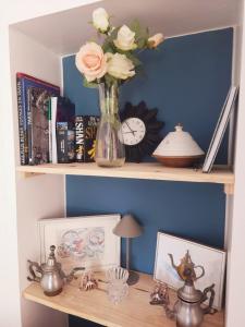 a vase of flowers on a shelf with a clock at Le Nid, petit studio cosy et central in Besançon
