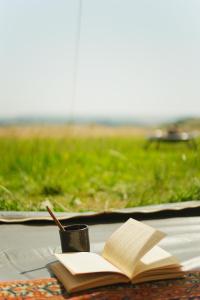 an open book and a cup with a pen on a table at Devon Belltents - Salcombe in Soar