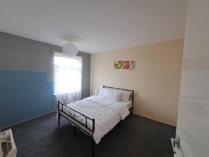 a bedroom with a bed with white sheets and a window at E Gardens Apartment in Nottingham