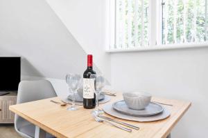 a wooden table with a bottle of wine and glasses at Addenbrookes Apartment in Trumpington +15 photos