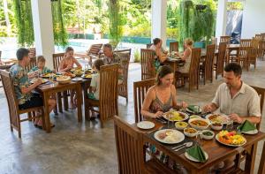 a group of people sitting at a table eating food at Lavish Resort Sigiriya in Inamaluwa