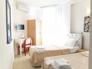 a hotel room with two beds and a desk at Nese Otel in Çeşme