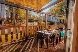a wooden deck with a table and chairs on it at Village Vacances de Combelles in Le Monastère