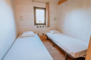 two beds in a small room with a window at Village Vacances de Combelles in Le Monastère