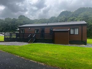 a log cabin with a porch and a grass yard at Crescent Lodge in Forton