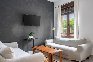 a living room with two couches and a tv on a wall at Little Yellow House in Gijón