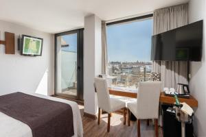 a hotel room with a bed and a desk and a window at Hotel Don Paco in Seville