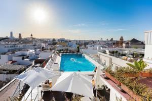 a pool on the roof of a building with umbrellas at Hotel Don Paco in Seville