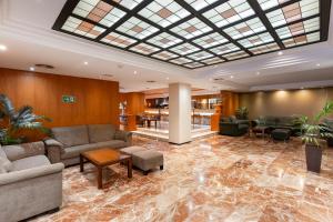 a lobby with couches and tables and a glass ceiling at Hotel Don Paco in Seville +90 photos