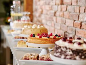 a row of cakes and pastries on plates on a table at Hotel & Restaurant Ole Liese in Panker