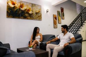 two people sitting on couches in a living room at Breedon Residence Hotel in Anuradhapura +48 photos