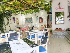 a restaurant with white tables and chairs and vines at Nese Otel in Çeşme +5 photos