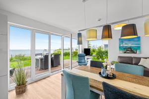 a living room with a dining table and a view of the ocean at Ferienwohnung WeitBlick Olpenitz in Olpenitz +21 photos