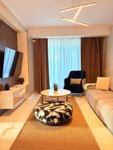 a living room with a couch and a table and a tv at F&Lrelax-Apartamente de închiriat aproape de plajă in Mamaia Sat/Năvodari