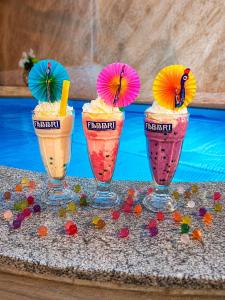 three milkshakes with umbrellas are sitting on a table at Хотел PERLA in Strelcha