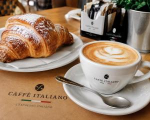 a cup of coffee and a croissant on a table at Il Faro Suites in Taranto +13 photos
