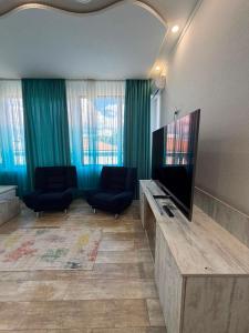 a living room with two chairs and a flat screen tv at Kaya Telavi in Telavi