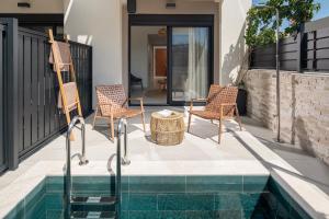 a patio with two chairs and a table next to a pool at Villas THALLO in Paradisos