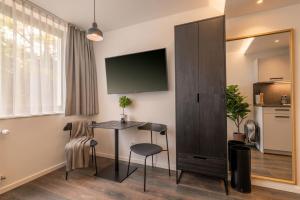 a room with a table and a tv on a wall at Limehome München in Munich