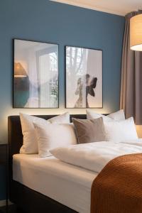 a bed with three pictures on the wall at Limehome München in Munich