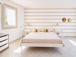 a white bed in a room with a striped wall at Maridea - Ondine in Ponza