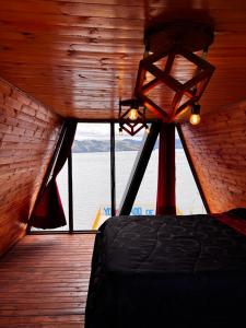 a bedroom with a bed and a view of the water at Lago de Tota GALAMPLAY lodge in Tota
