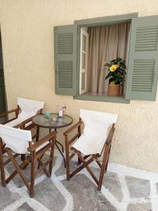 a patio with three chairs and a table and a window at Feidiou 1, vol I in Egina +20 photos