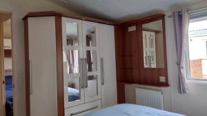 a bedroom with a wooden cabinet and a bed at Sandpiper Aspen 9 in Peterhead