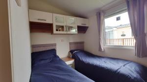 a small bedroom with two beds and a window at Sandpiper Aspen 9 in Peterhead +5 photos