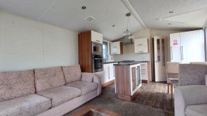 a living room with a couch and a kitchen at Sandpiper Aspen 9 in Peterhead