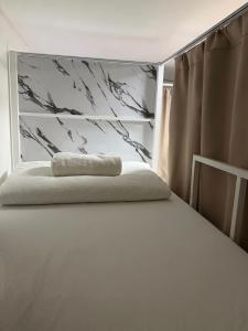 a bed with a pillow on top of it at Best Inn Hostel and Café Patong Beach in Patong Beach