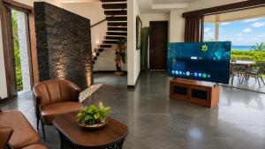 a living room with a television and a table and chairs at Villa Layar with Private Pool and Ocean View in Lajor