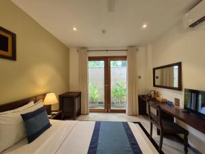 a bedroom with a bed and a desk with a television at Coastal Villa Mirissa in Mirissa