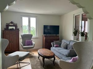 a living room with a couch and two chairs at Au parfum des roses in Gunstett
