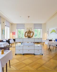 a dining room with white tables and a chandelier at Hôtel Alpes & Lac in Neuchâtel