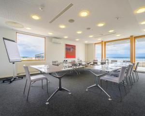 a conference room with tables and chairs and a screen at Hôtel Alpes & Lac in Neuchâtel