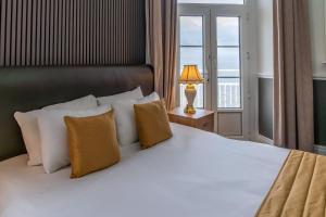 a bedroom with a large white bed with a window at The Grand Hotel in Llandudno