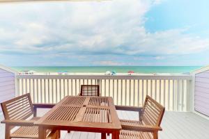 a wooden table and chairs on a deck with the beach at Dune Our Thing in Kure Beach