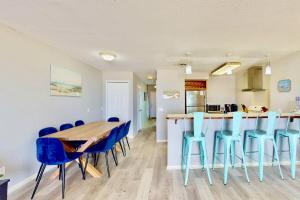 a kitchen and dining room with a wooden table and blue chairs at Dune Our Thing in Kure Beach +36 photos