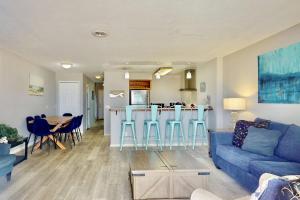 a living room with a blue couch and a kitchen at Dune Our Thing in Kure Beach