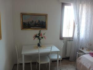 a white dining room table with a vase of flowers on it at appartamento 4 piano in Chioggia