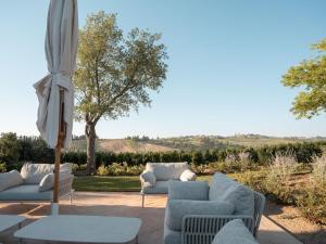 a patio with two couches and an umbrella at Tenuta Bartoli in San Gimignano