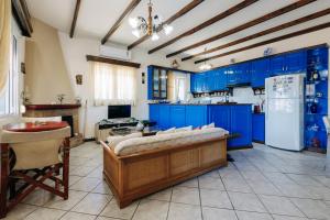 a large kitchen with blue cabinets and a refrigerator at Limnia View in LimiÃ¡ +13 photos