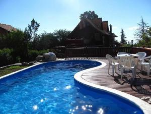 a swimming pool with chairs and a table and a house at Casita de Belén in Merlo