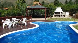 a deck with a table and chairs next to a pool at Casita de Belén in Merlo +1 photo