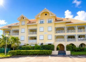 a large yellow building with bushes in a parking lot at Appartement Coco Antilles ,vue mer, terrasse couverte 25m2,plage à pied in Sainte-Luce