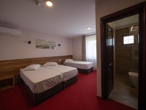 a hotel room with two beds and a bath tub at Pensiunea Florica in Piteşti